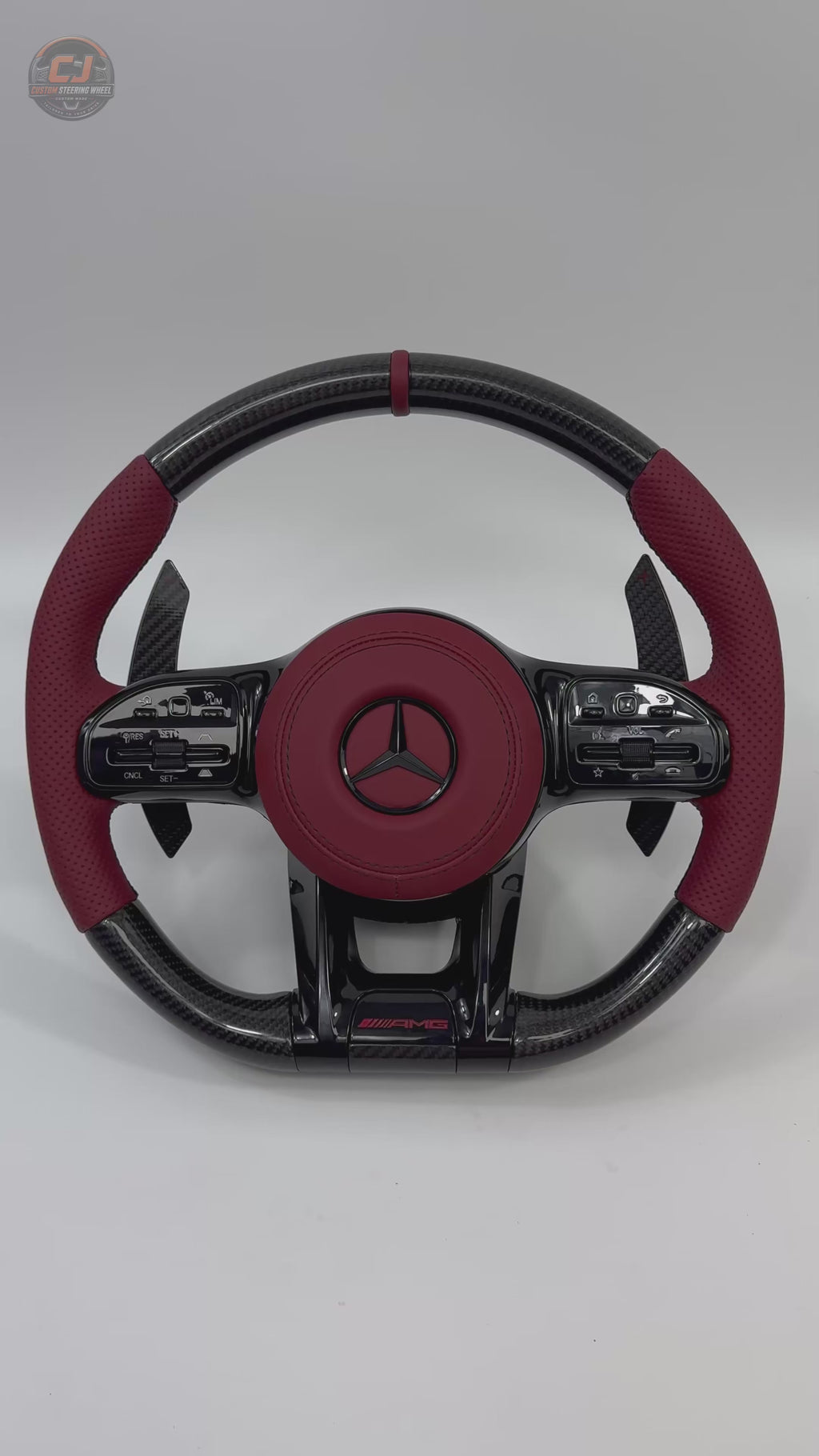 White background video of Mercedes AMG custom carbon fiber steering wheel with red perforated leather grips and sporty paddle shifters for W117 W176 W177 W203 W204 W205 W211 W212 W213 W218 C43 C63 C200 C300 by CJ Mod Garage