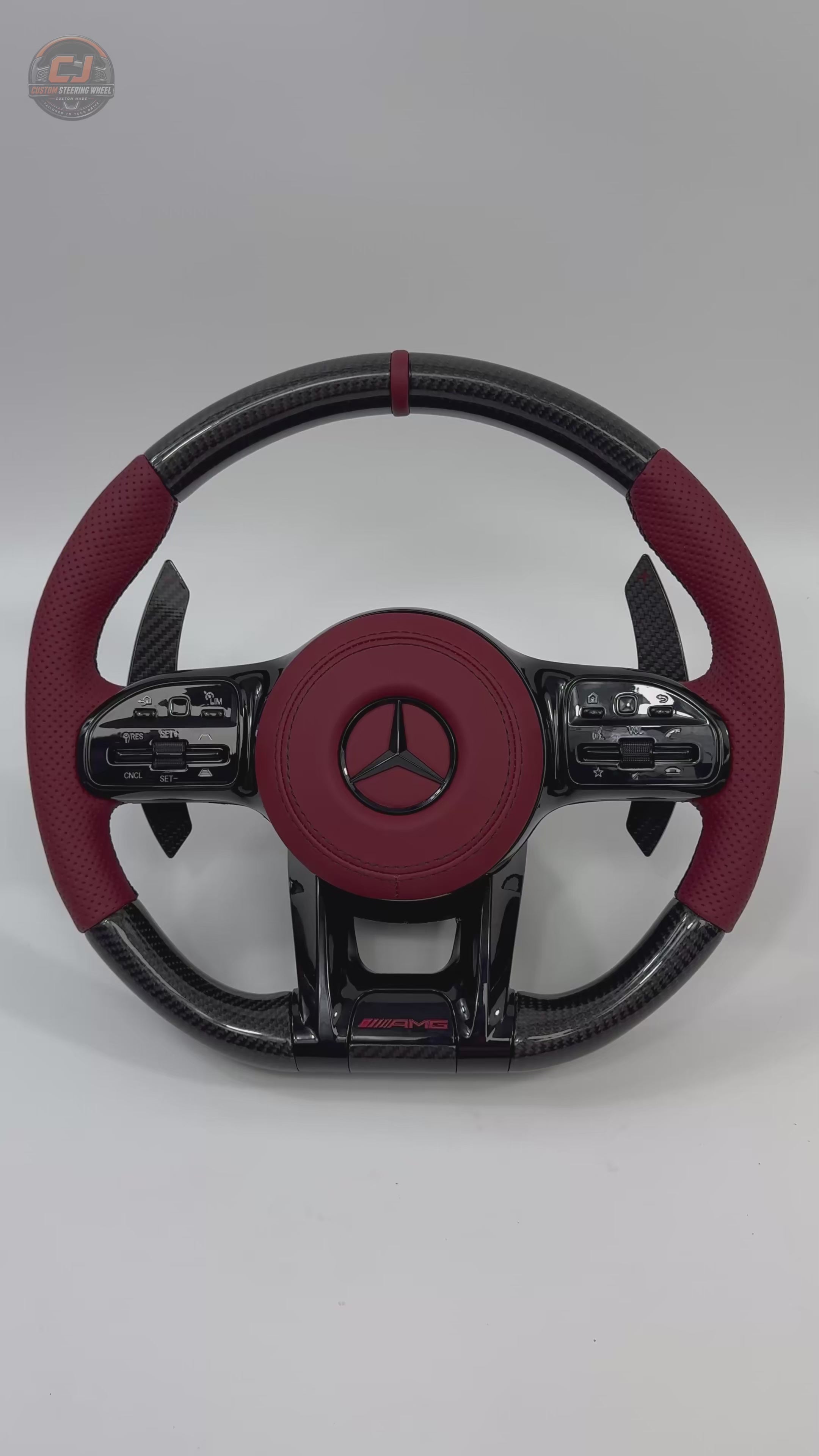 White background video of Mercedes AMG custom carbon fiber steering wheel with red perforated leather grips and sporty paddle shifters for W117 W176 W177 W203 W204 W205 W211 W212 W213 W218 C43 C63 C200 C300 by CJ Mod Garage