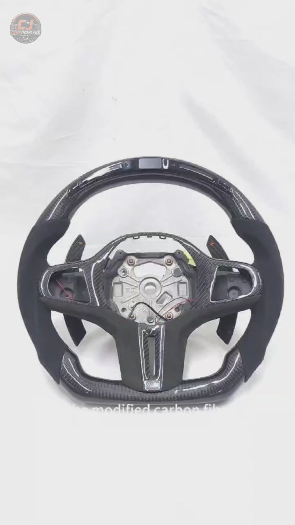 White background product showcase video of CJ Mod Garage BMW G-series LED carbon fiber steering wheel with integrated shift light display, Alcantara grips, carbon paddle shifters, and flat-bottom M-style performance design compatible with BMW G02 G05 G06 G09 G11 G12 G15 G20 G22 G28 G29 G30 G38 G80 G82 F40 F90