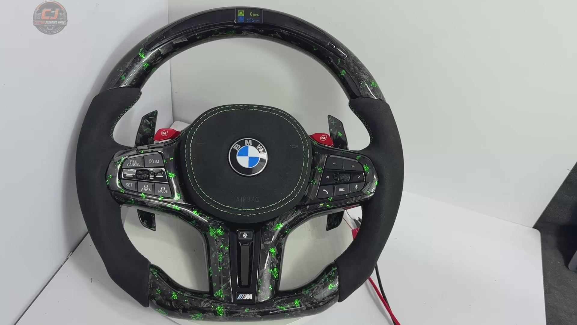 White background video of a BMW custom forged carbon steering wheel with green flakes, LED RPM display, M1 M2 buttons and Alcantara grips for BMW G02 G05 G06 G09 G11 G12 G15 G20 G22 G28 G29 G30 G38 G80 G82 F40 F90 models by CJ Mod Garage