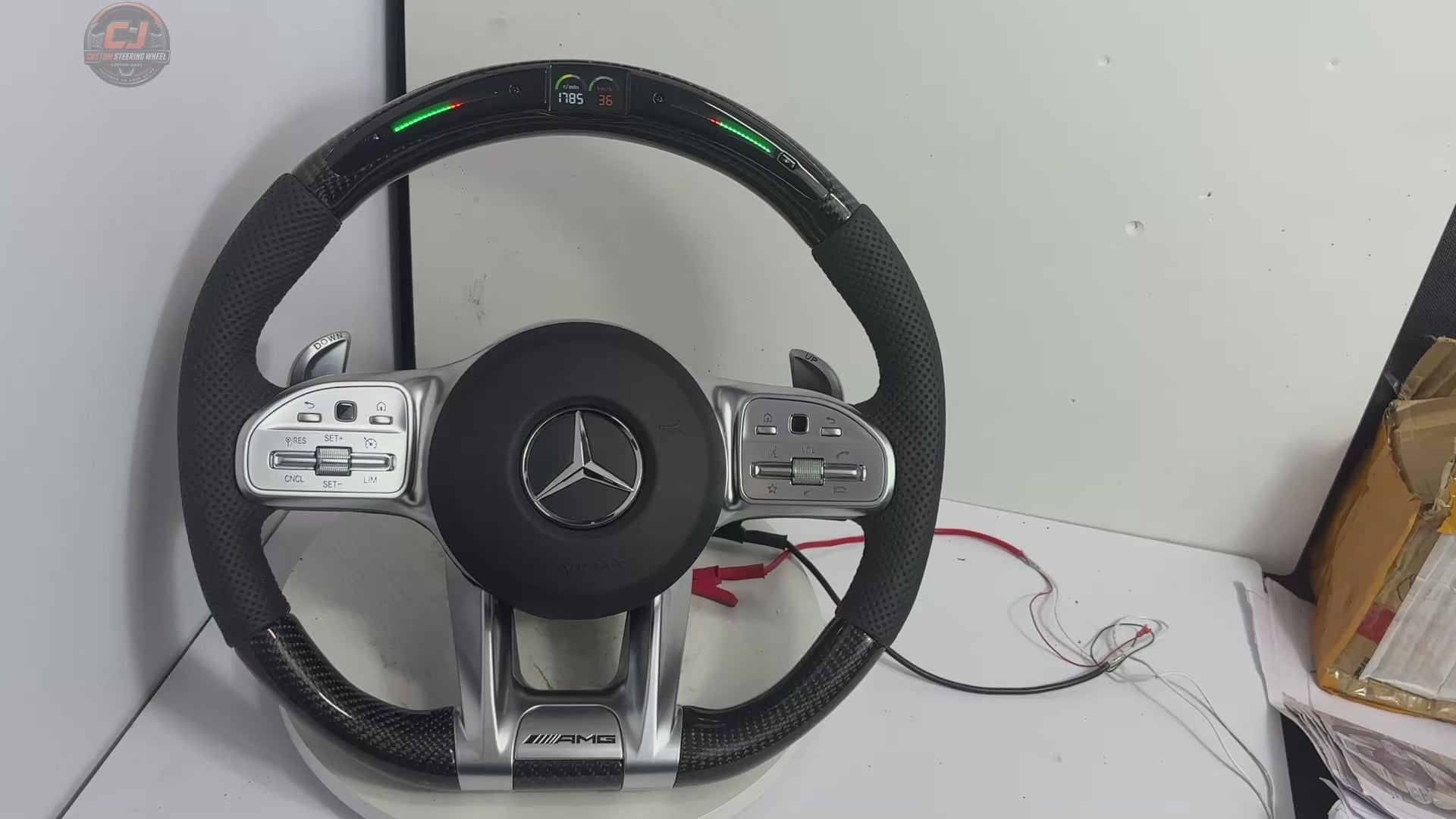 White background video showing Mercedes AMG carbon fiber steering wheel with LED shift light RPM screen perforated leather grips silver sport spokes and paddle shifters for W117 W176 W177 W203 W204 W205 W211 W212 W213 W218 C43 C63 C200 C300 by CJ Mod Garage