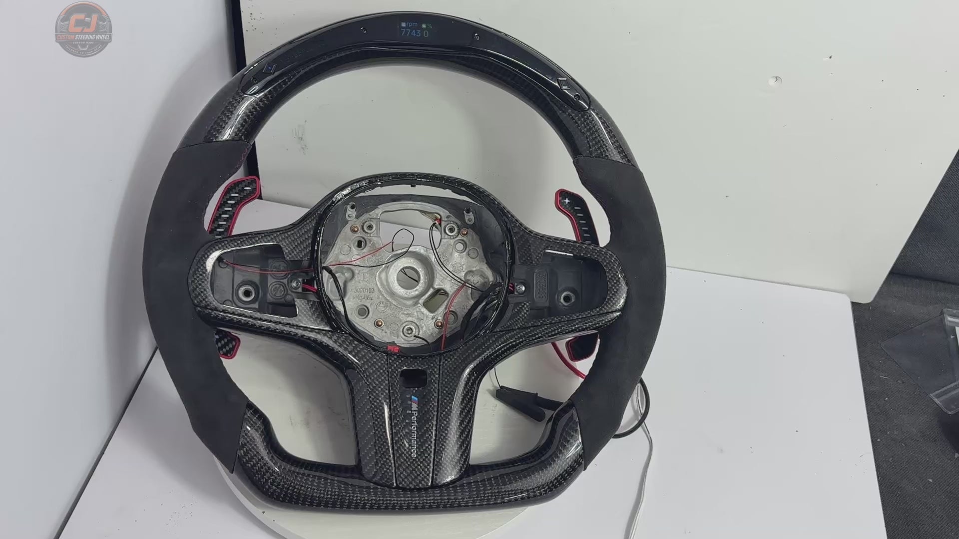 White background showcase video of BMW G-chassis custom carbon fiber steering wheel featuring LED shift lights, Alcantara sport grips, illuminated paddle shifters, and performance racing design compatible with BMW G02 G05 G06 G09 G11 G12 G15 G20 G22 G28 G29 G30 G38 G80 G82 F40 F90