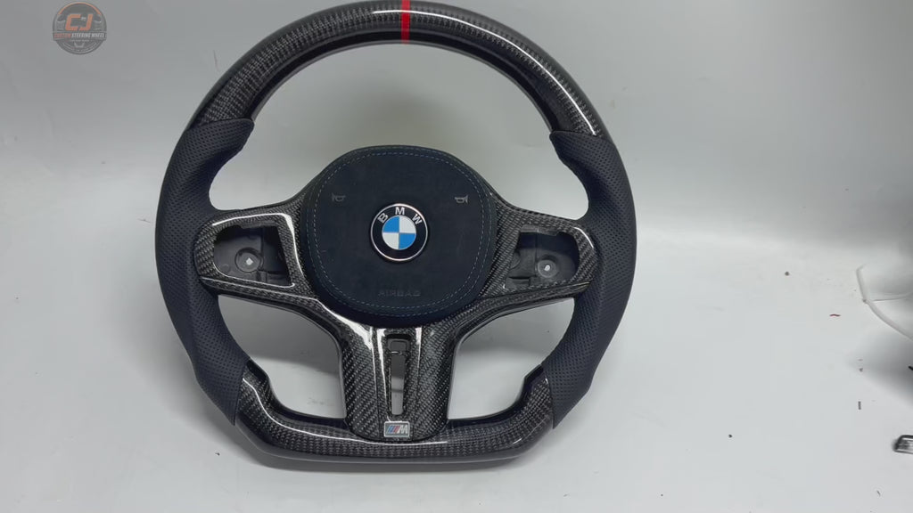 White background showcase video of custom BMW G-series carbon fiber steering wheel with perforated leather grips, blue stitching, flat-bottom OEM+ performance design, and red center stripe compatible with BMW G02 G05 G06 G09 G11 G12 G15 G20 G22 G28 G29 G30 G38 G80 G82 F40 F90
