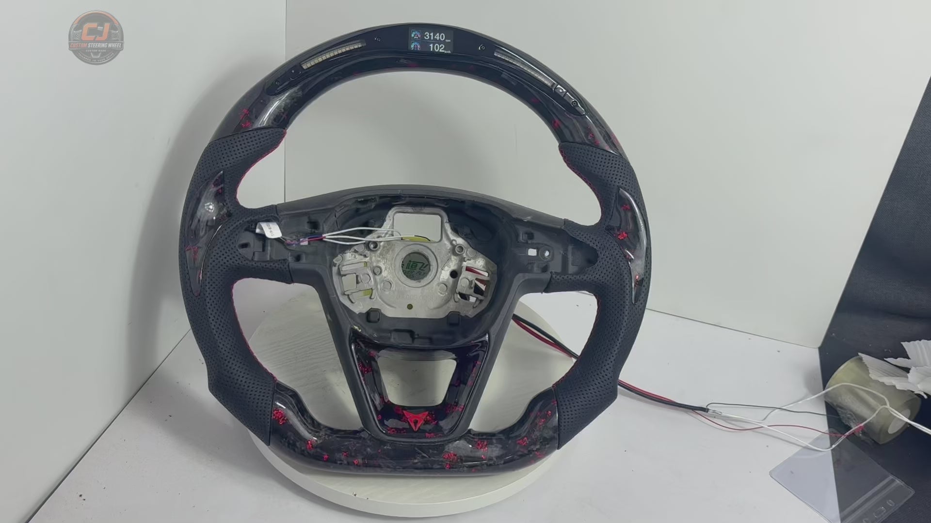 Product showcase video of Seat Leon Cupra forged carbon fiber steering wheel with red flake carbon finish LED shift light display perforated leather grips and custom flat bottom construction by CJ Mod Garage