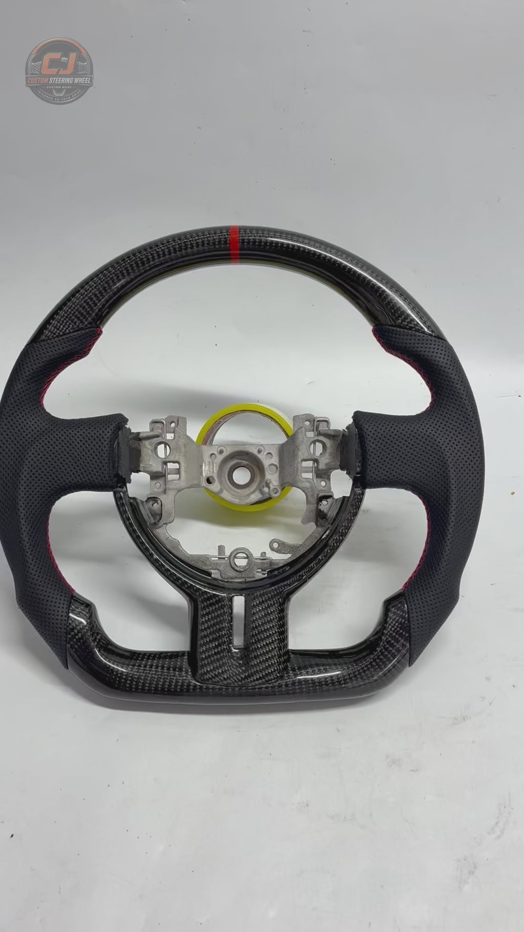 Product showcase video of Toyota GT86 carbon fiber steering wheel with glossy weave finish, perforated leather grips, red contrast stitching and flat-bottom design by CJ Mod Garage