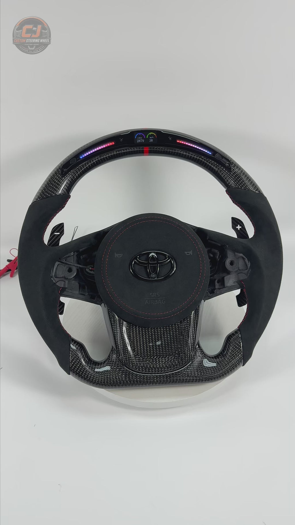 360-degree product video of Toyota GR Supra A90 A91 carbon fiber steering wheel with Alcantara grips, LED shift light display, magnetic paddle shifters, red stitching and custom performance styling by CJ Mod Garage