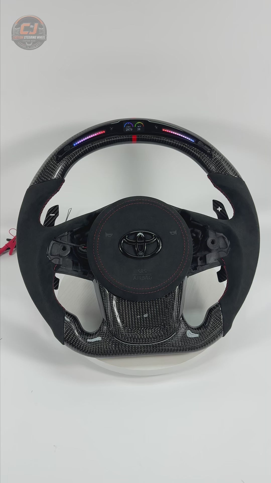 360-degree product video of Toyota GR Supra A90 A91 carbon fiber steering wheel with Alcantara grips, LED shift light display, magnetic paddle shifters, red stitching and custom performance styling by CJ Mod Garage