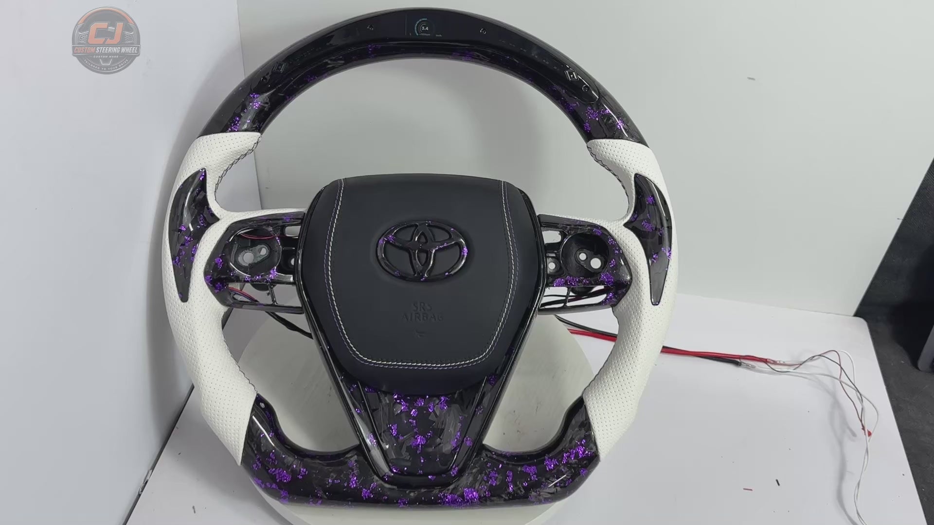 Studio showcase video of Toyota Camry forged carbon fiber steering wheel with purple flake accents, white perforated leather grips, custom stitching and LED shift light system by CJ Mod Garage