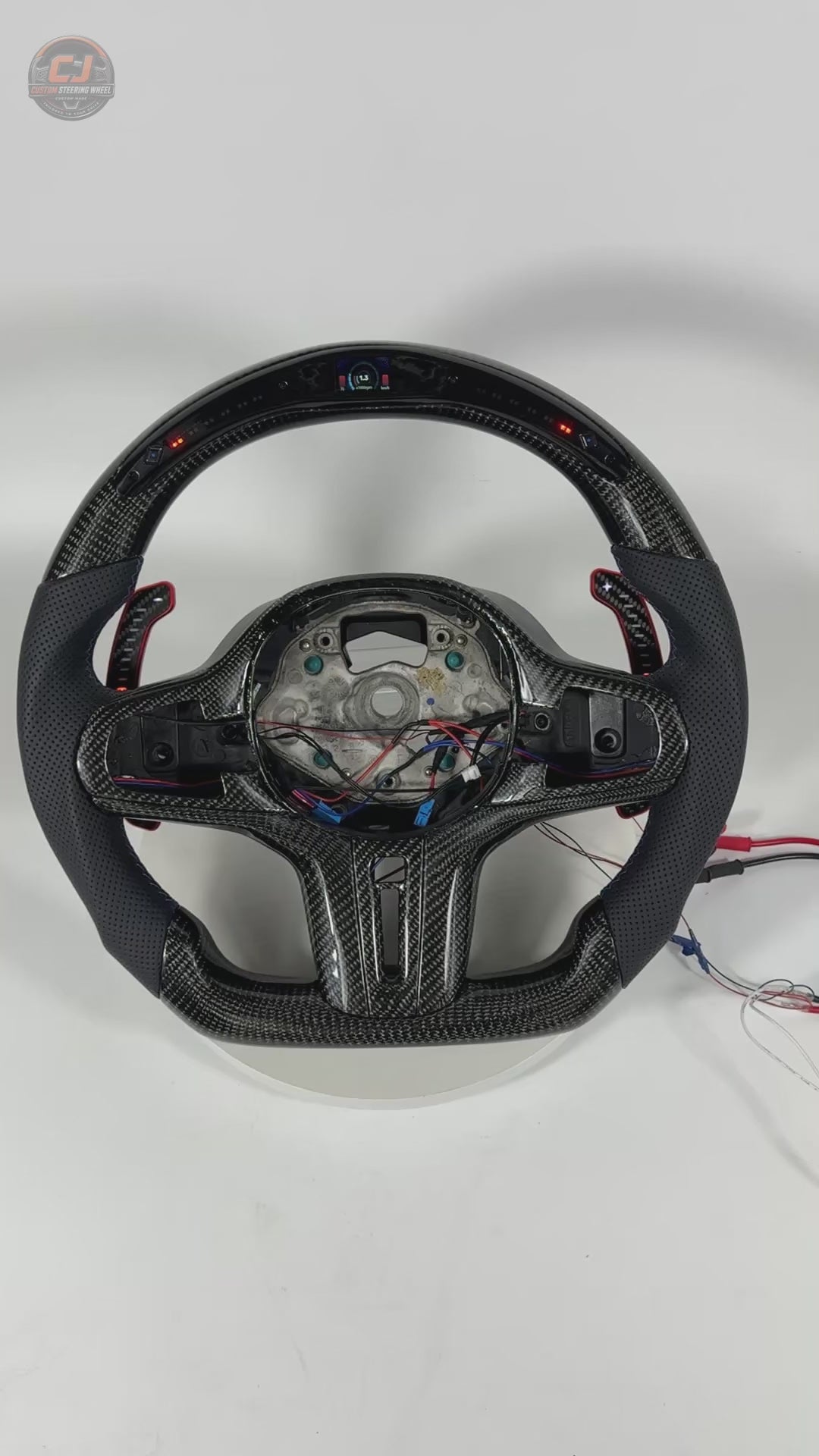 White studio video showcasing BMW custom carbon steering wheel with LED shift lights, perforated leather grips and digital display for BMW G02 G05 G06 G09 G11 G12 G15 G20 G22 G28 G29 G30 G38 G80 G82 F40 F90 by CJ Mod Garage